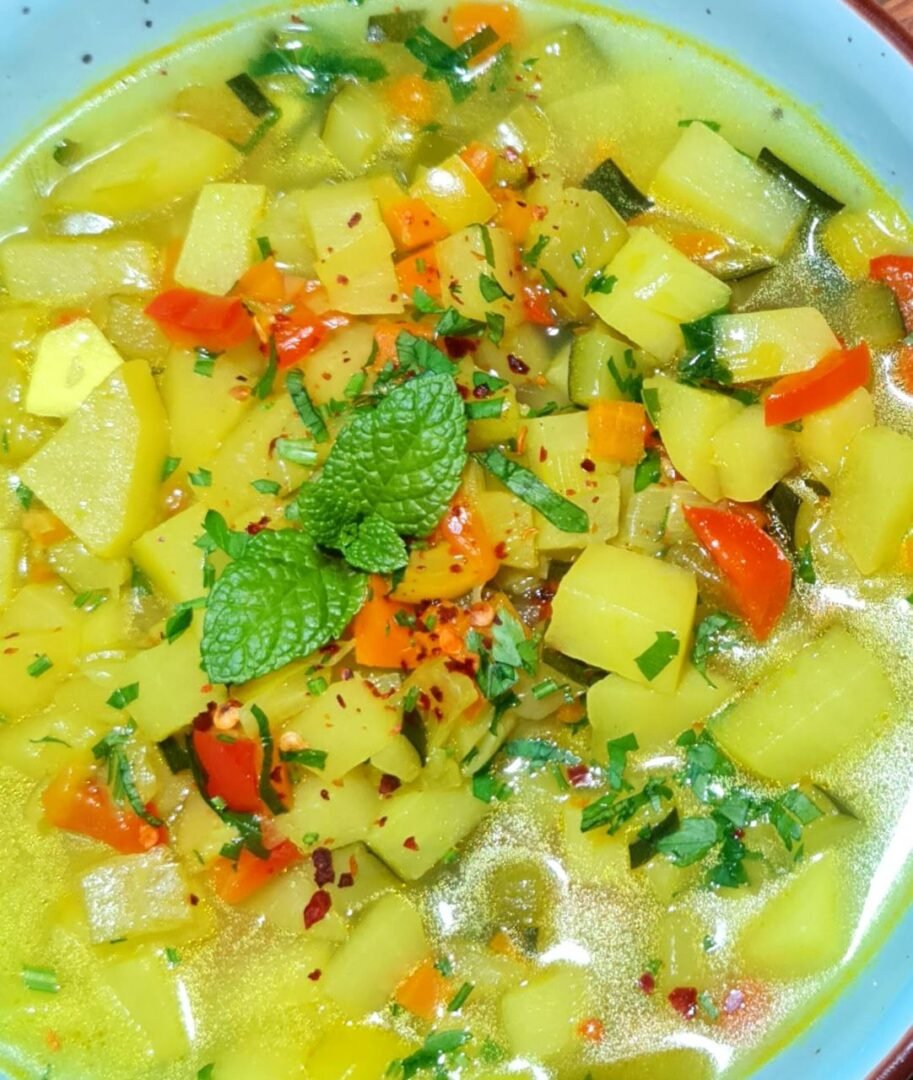 a bowl of soup with vegetables and herbs