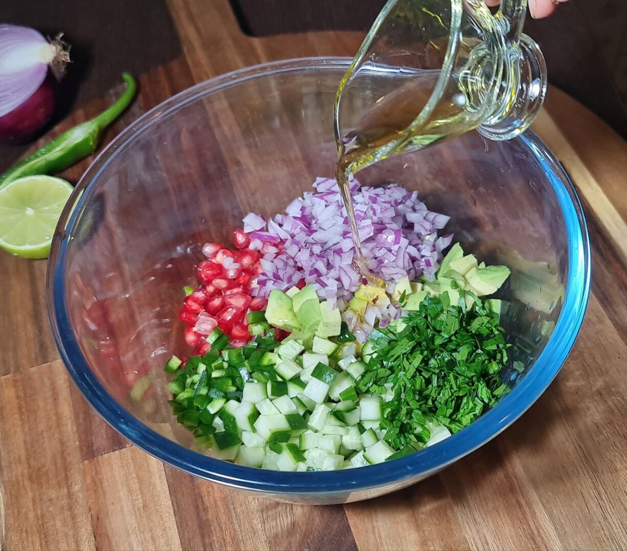 A bowl of colorful pomegranate salsa with diced cucumber, red onion, pomegranate seeds, and avocado, surrounded by fresh ingredients. Fresh and vibrant pomegranate salsa with diced cucumber, red onion, pomegranate seeds, and avocado.