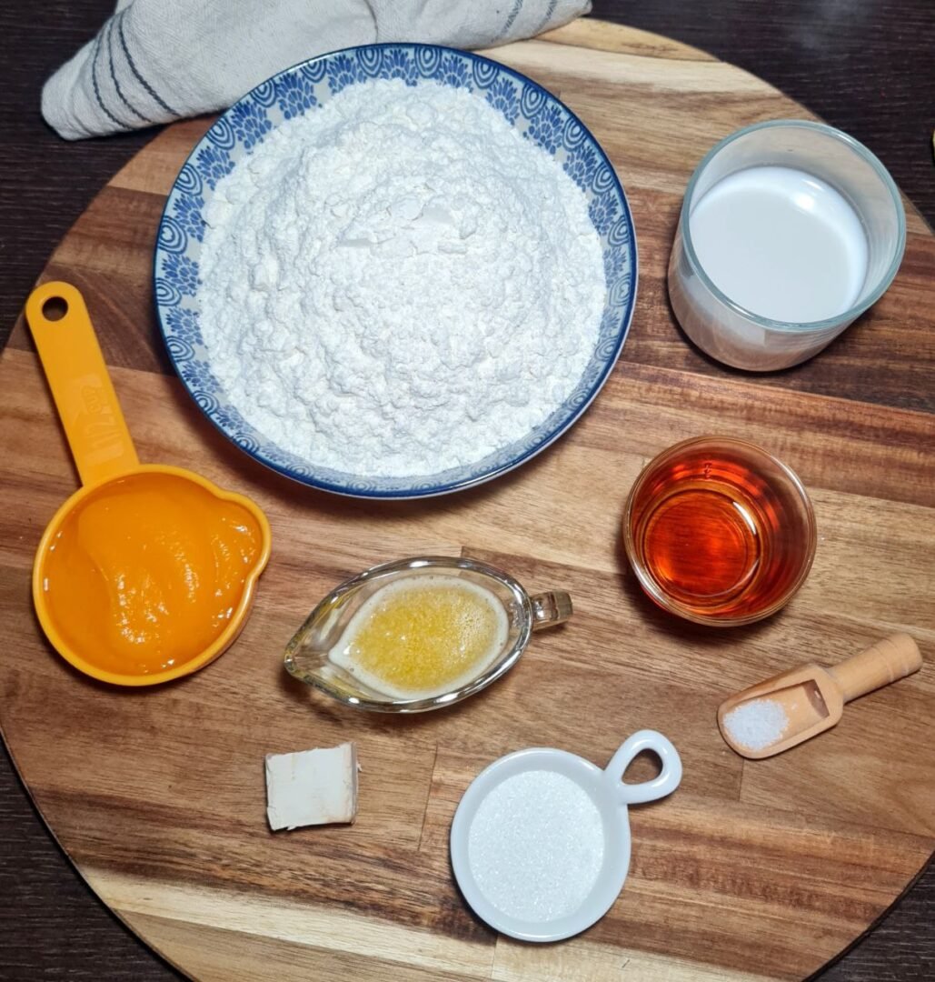 Ingredients for pumpkin dinner rolls including flour, pumpkin puree, and milk.  Essential ingredients for making pumpkin dinner rolls.