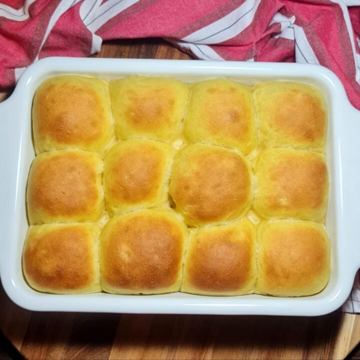 Golden pumpkin dinner rolls baked in a white dish. Fluffy and golden pumpkin dinner rolls, fresh out of the oven.