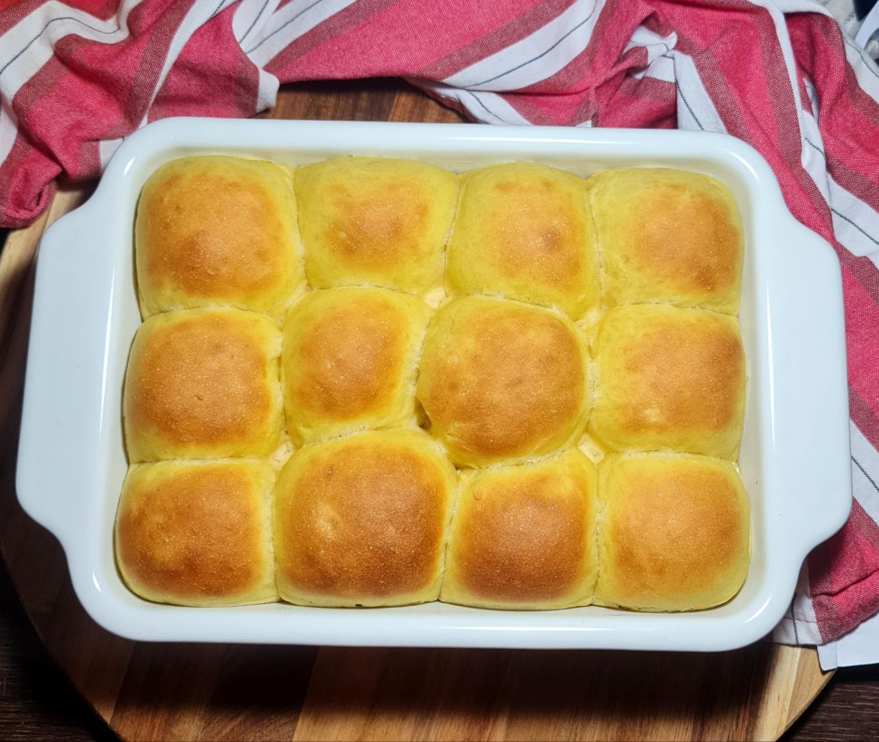 Golden pumpkin dinner rolls baked in a white dish. Fluffy and golden pumpkin dinner rolls, fresh out of the oven.