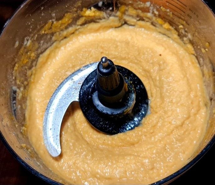 Creamy pumpkin hummus being blended in a food processor. Smooth and creamy pumpkin hummus blending to perfection.