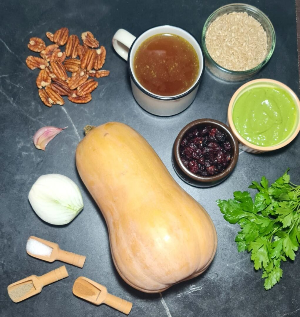 Ingredients for stuffed butternut squash, including a butternut squash, rice, pecans, vegetable broth, cranberries, green sauce, onion, garlic, and seasonings. Ingredients for creating a delicious stuffed butternut squash.