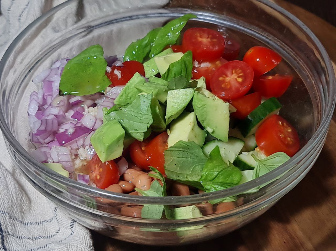 A bowl of colorful three bean salad with a mix of beans, vegetables, and fresh herbs.