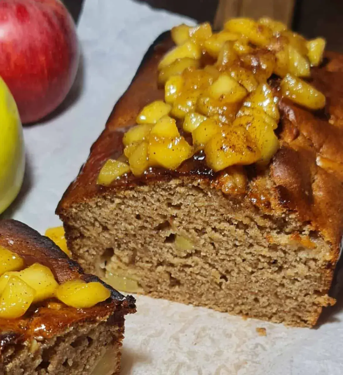 A loaf of simple vegan apple cake baking in the oven with visible apple chunks on top.