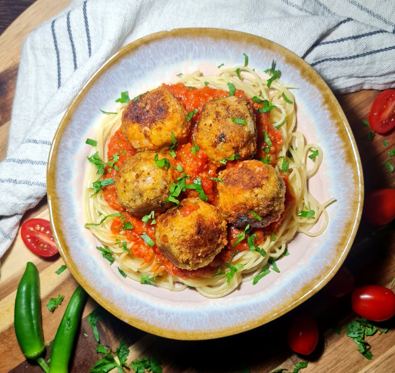 A plate of vegan chickpea meatballs served over spaghetti with marinara sauce, garnished with fresh parsley.