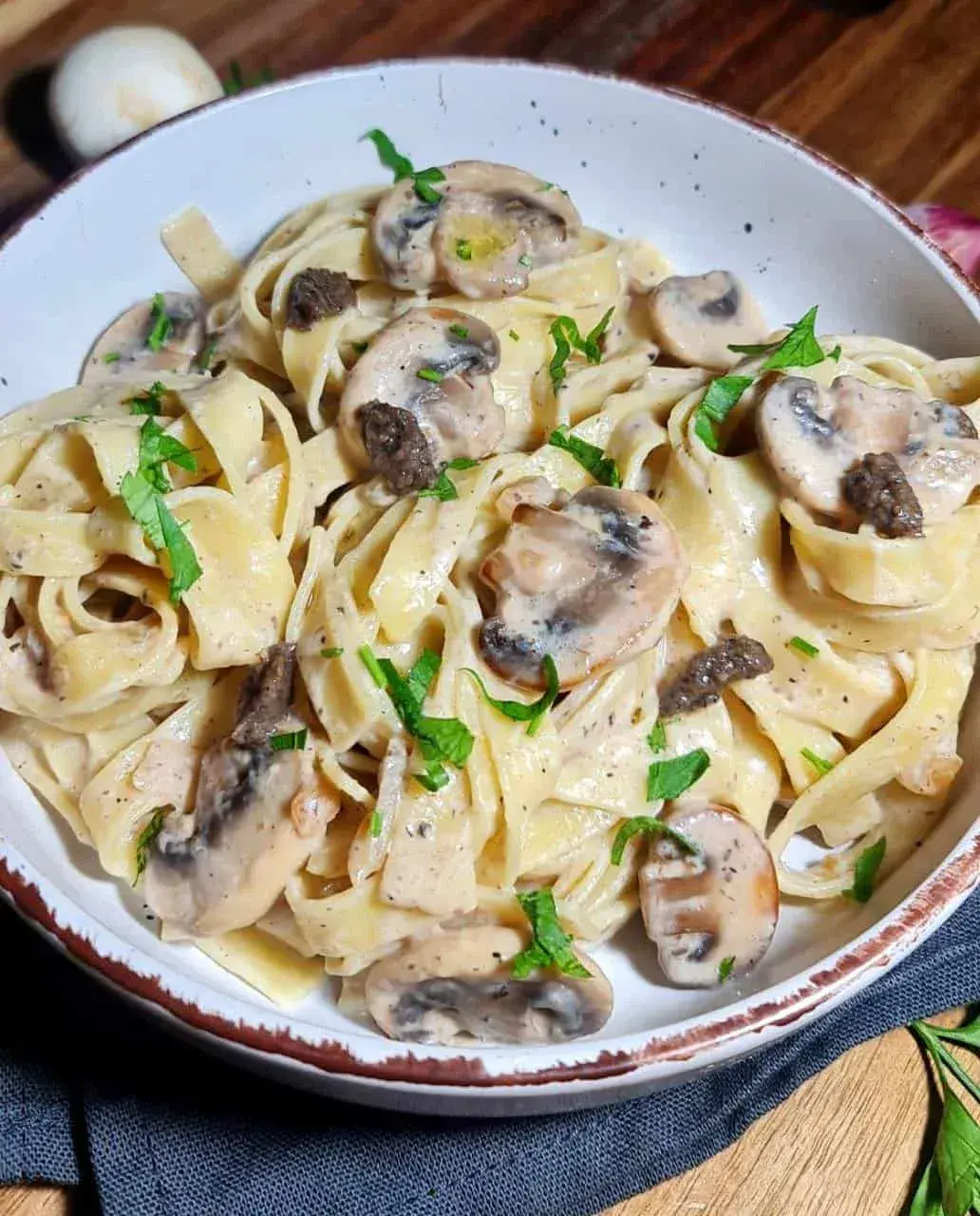 A bowl of vegan creamy mushroom and truffle pasta garnished with fresh herbs. Delicious vegan creamy mushroom and truffle pasta, perfect for a comforting meal.