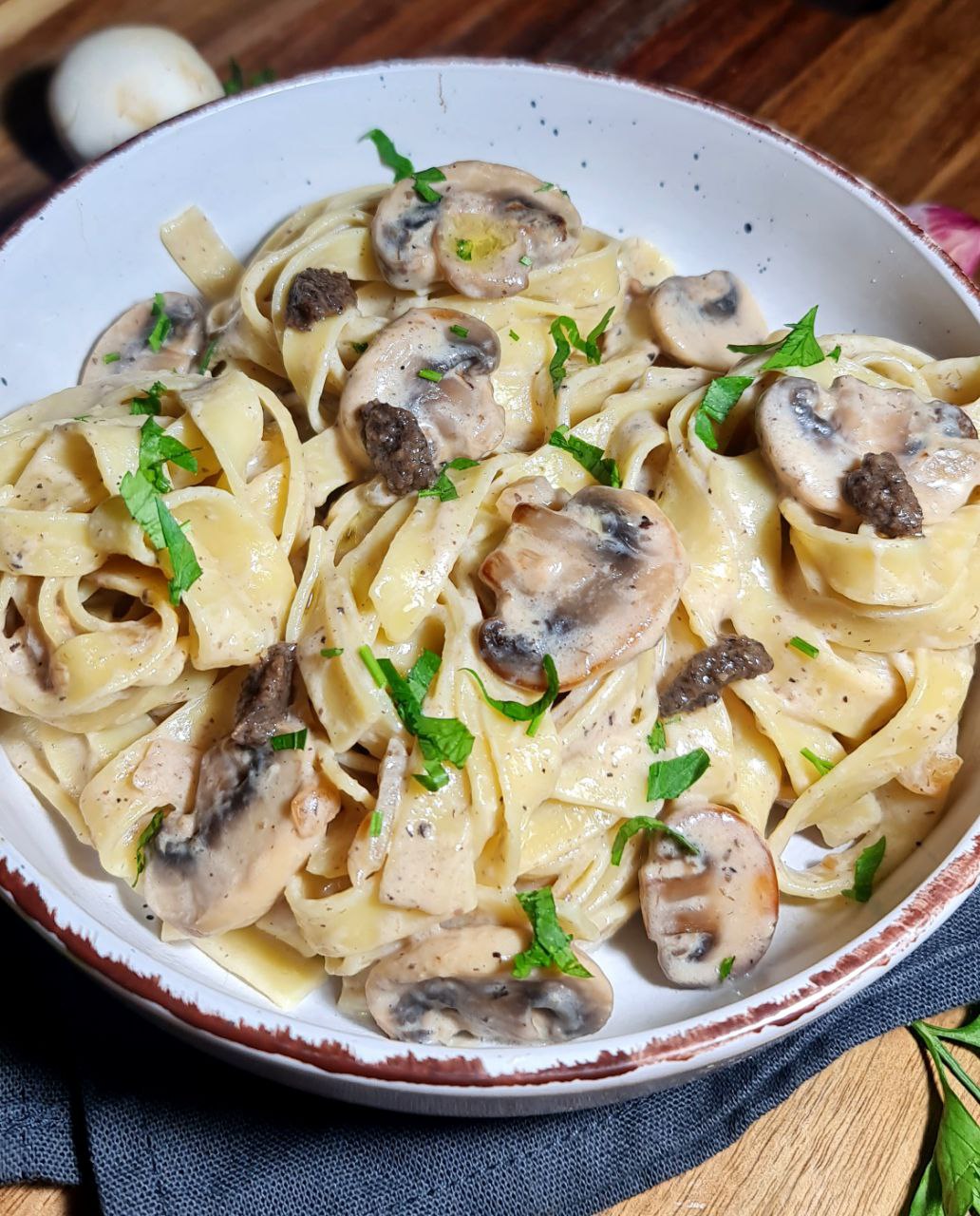 A bowl of vegan creamy mushroom and truffle pasta garnished with fresh herbs. Delicious vegan creamy mushroom and truffle pasta, perfect for a comforting meal.