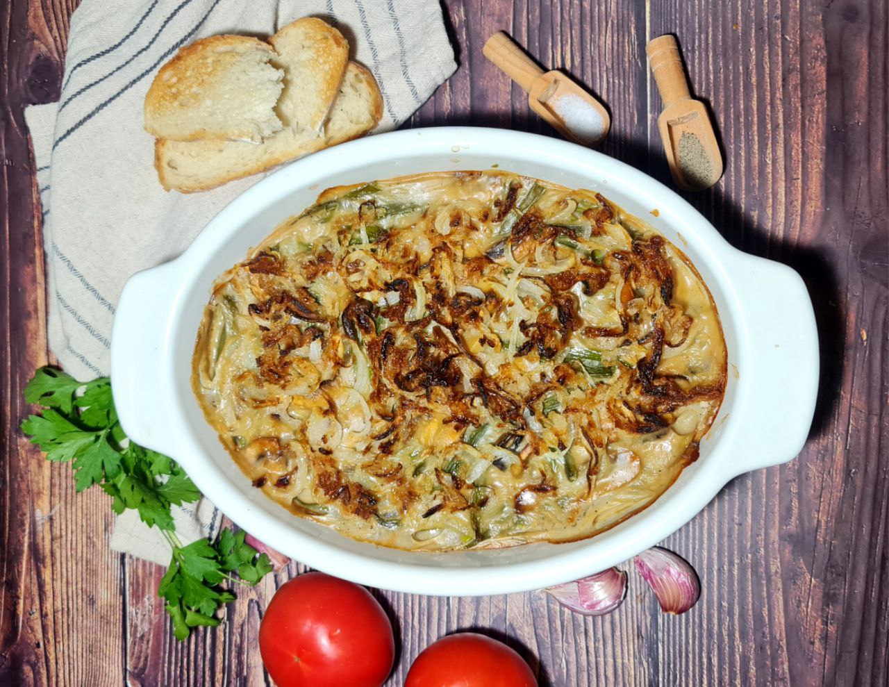 Freshly baked vegan green bean casserole in a white baking dish. Creamy, flavorful vegan green bean casserole topped with crispy onions, perfect for holiday dinners.