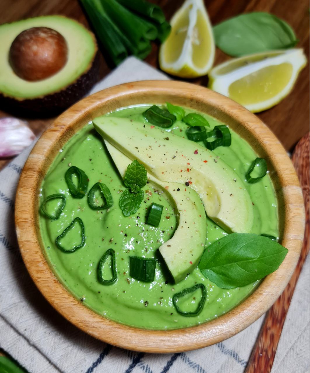 Vegan green goddess dressing in a wooden bowl topped with avocado, mint, and green onion. Creamy vegan green goddess dressing served and garnished with fresh toppings.