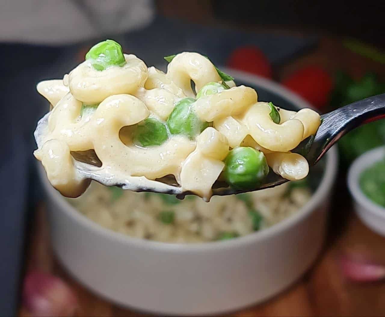 Close-up of a spoonful of creamy vegan macaroni and peas, showing vibrant green peas and creamy sauce. A delicious bite of Vegan Mac and Peas ready to be savored.