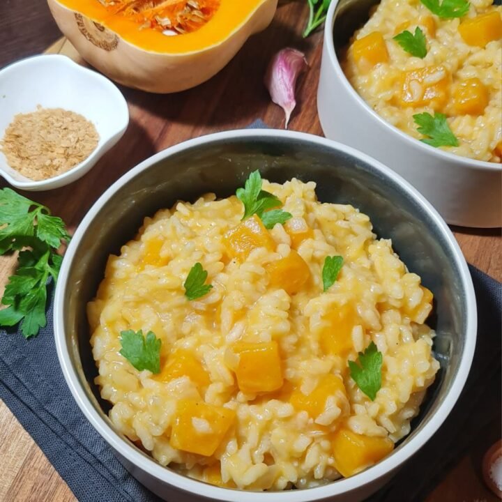 Two bowls of vegan pumpkin risotto with butternut squash and parsley garnish. Creamy and delicious vegan pumpkin risotto garnished with fresh parsley.