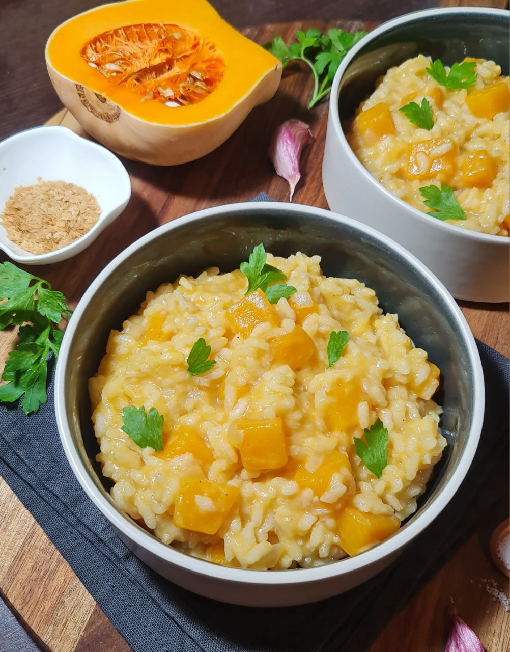 Two bowls of vegan pumpkin risotto with butternut squash and parsley garnish. Creamy and delicious vegan pumpkin risotto garnished with fresh parsley.