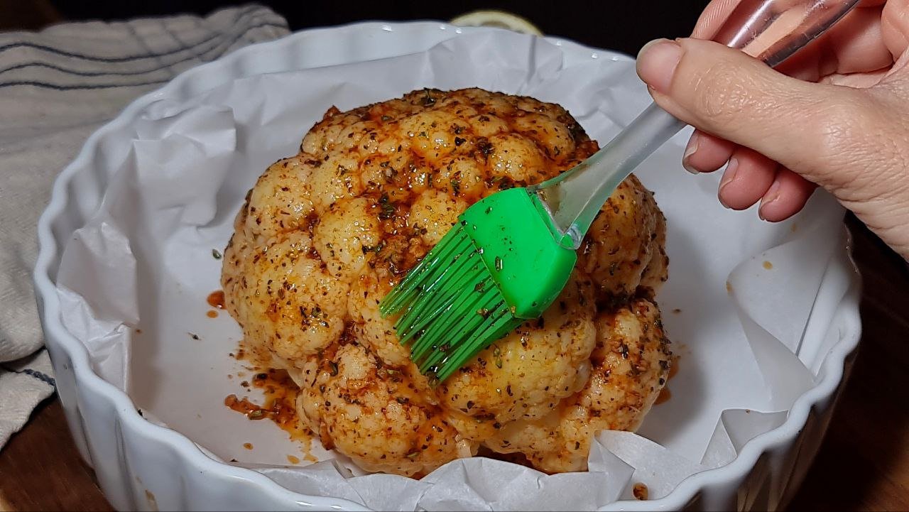 a person brushing cauliflower with a green brush