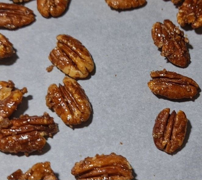 Close-up of candied pecans on parchment paper.