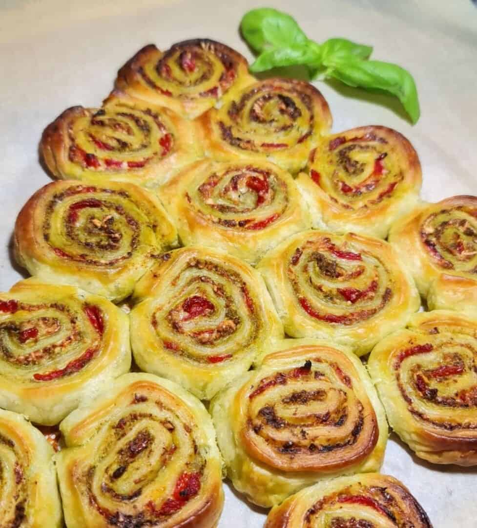 Christmas pinwheel appetizer made with puff pastry, pesto, and roasted red peppers, arranged in a tree shape.