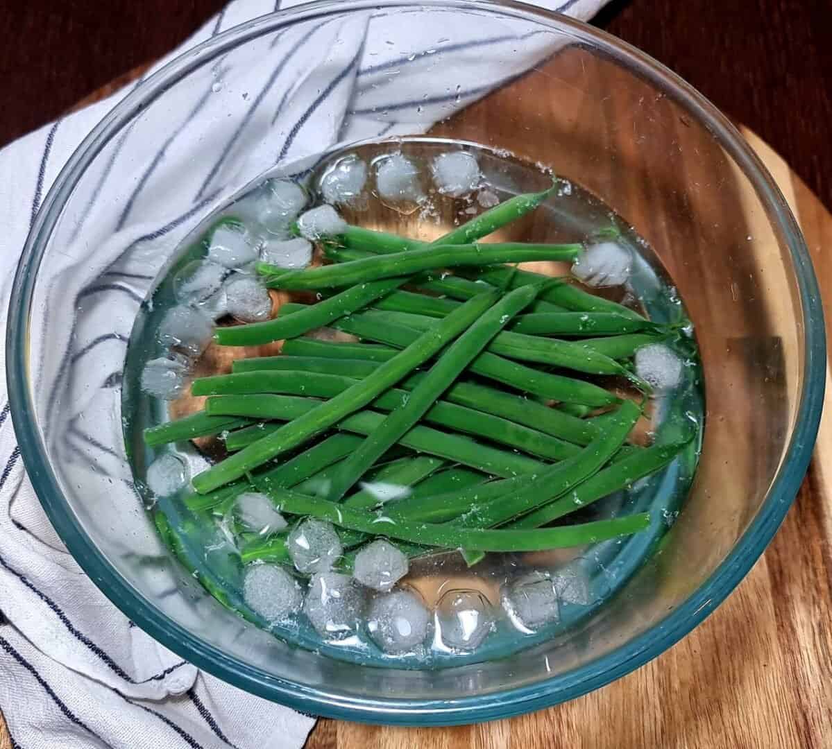 how to cook green beans - a bowl of green beans with ice and water