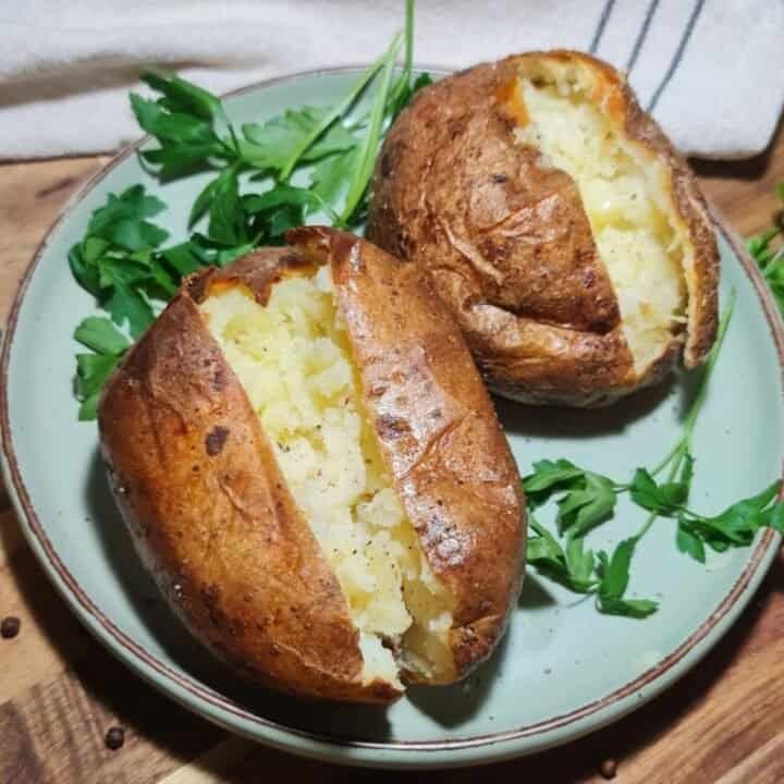 Close-up of perfectly baked potatoes with crispy skin and fluffy interior, garnished with fresh parsley.