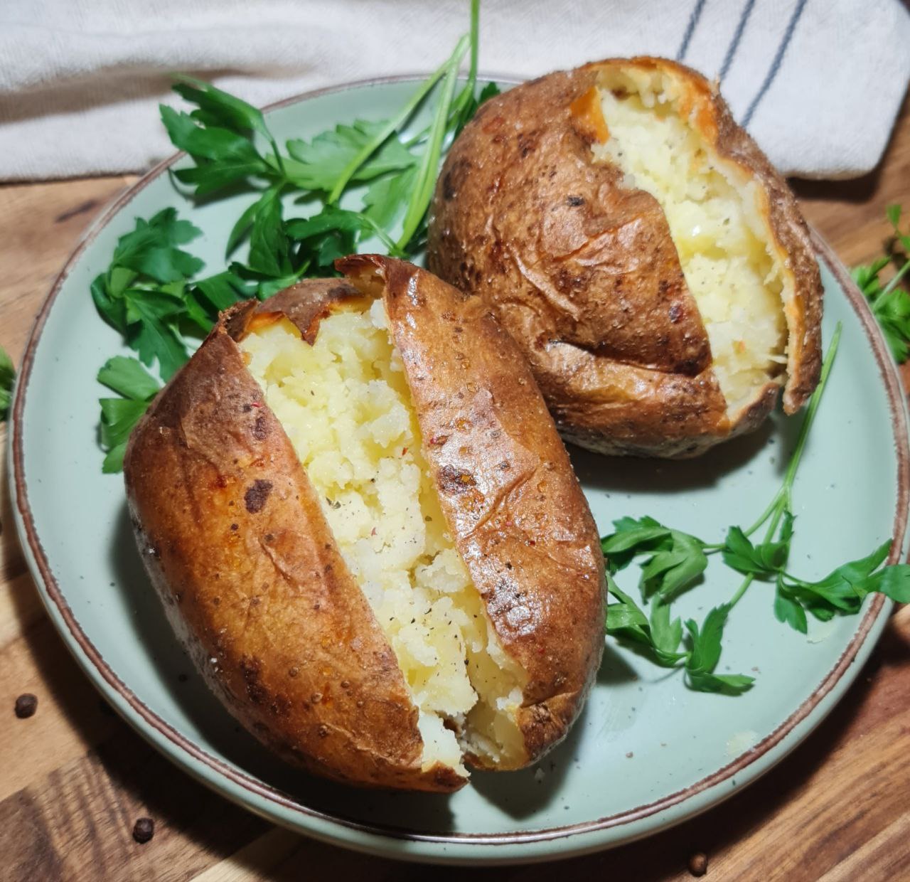 Close-up of perfectly baked potatoes with crispy skin and fluffy interior, garnished with fresh parsley.