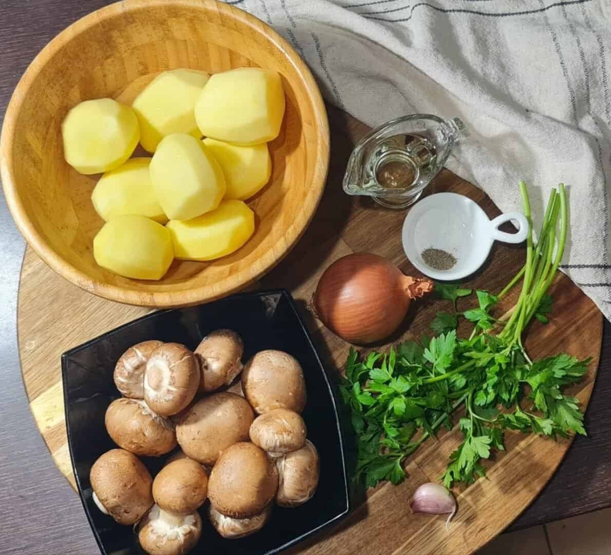 Ingredients for a potato mushroom skillet including peeled potatoes, mushrooms, onion, garlic, parsley, oil, salt, and pepper.