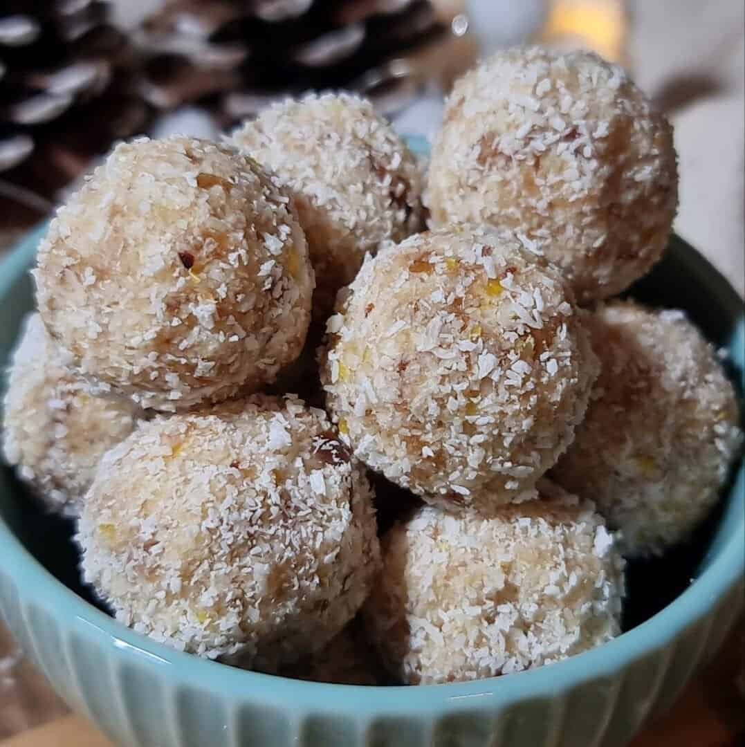 A bowl filled with vegan lemon coconut balls, coated in shredded coconut.