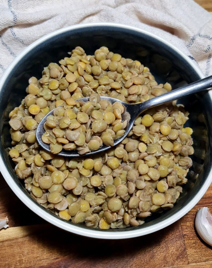 A bowl of cooked lentils with a spoon.