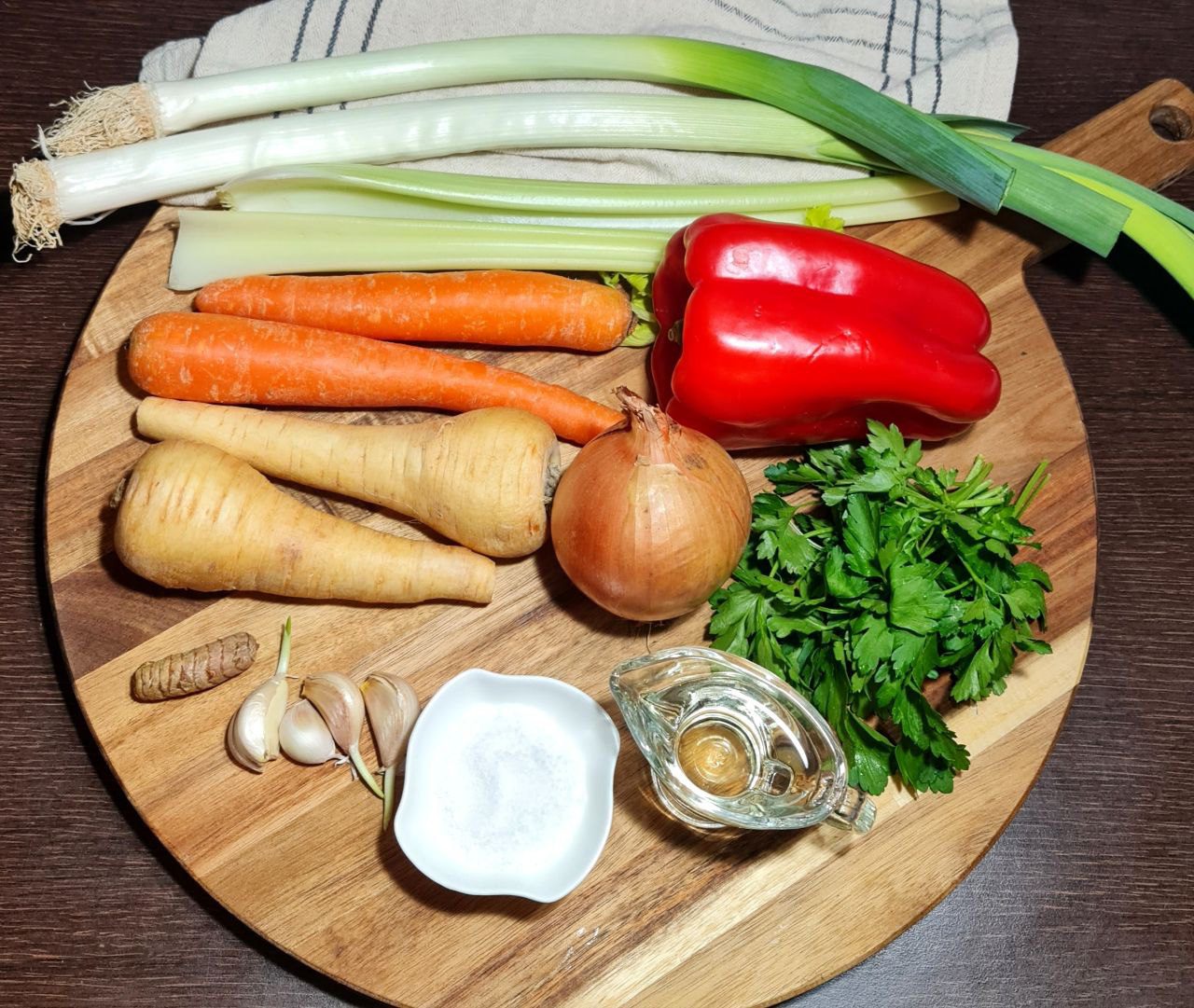 Fresh vegetables and ingredients for homemade vegetable broth cubes on a wooden cutting board.