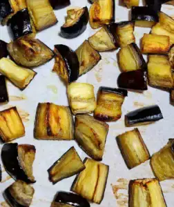 Oven-roasted eggplant cubes on a baking sheet.