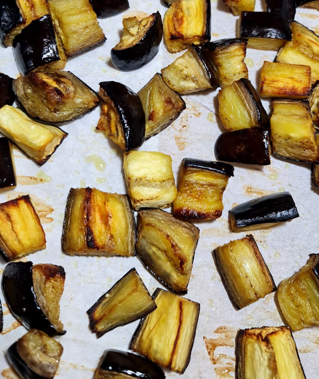 Oven-roasted eggplant cubes on a baking sheet.