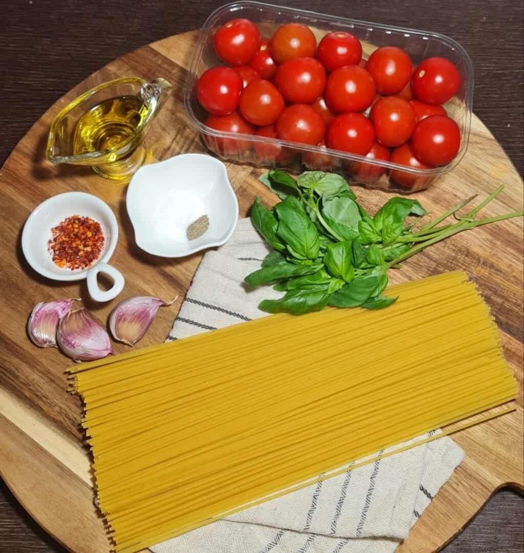 Ingredients for pasta with cherry tomatoes recipe including cherry tomatoes, spaghetti, garlic, basil, olive oil, red pepper flakes, and black pepper.