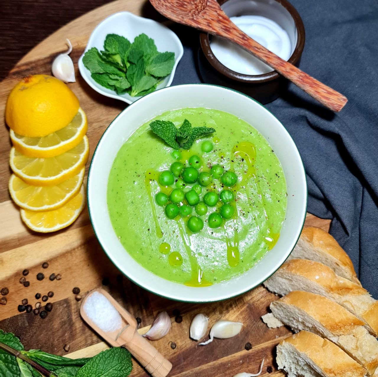 Bowl of green pea and mint soup garnished with fresh peas, mint, and olive oil