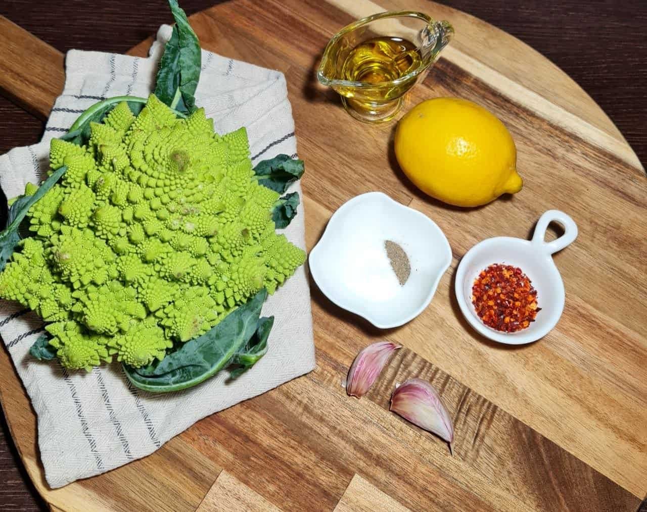 Ingredients for roasted Romanesco recipe including Romanesco broccoli, lemon, olive oil, garlic, salt, pepper, and red pepper flakes.