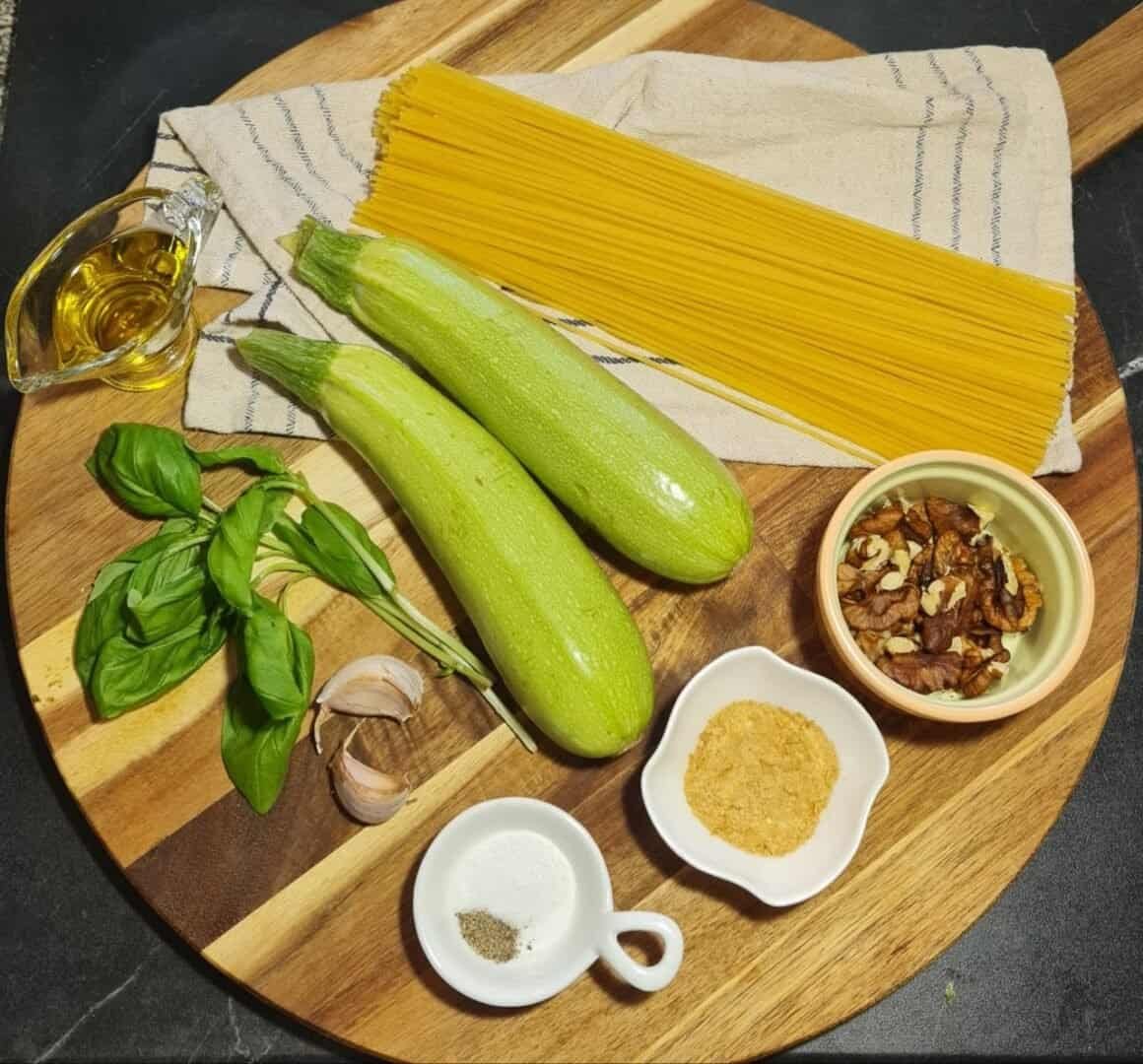  Ingredients for vegan spaghetti alla Nerano recipe including zucchini, spaghetti, basil, garlic, walnuts, nutritional yeast, salt, pepper, and olive oil.