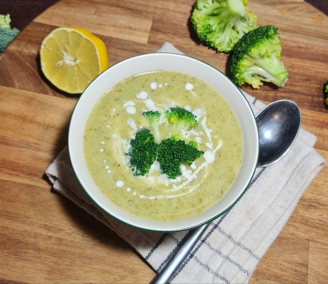 A ladle lifting creamy vegan broccoli soup with a broccoli floret from a pot.