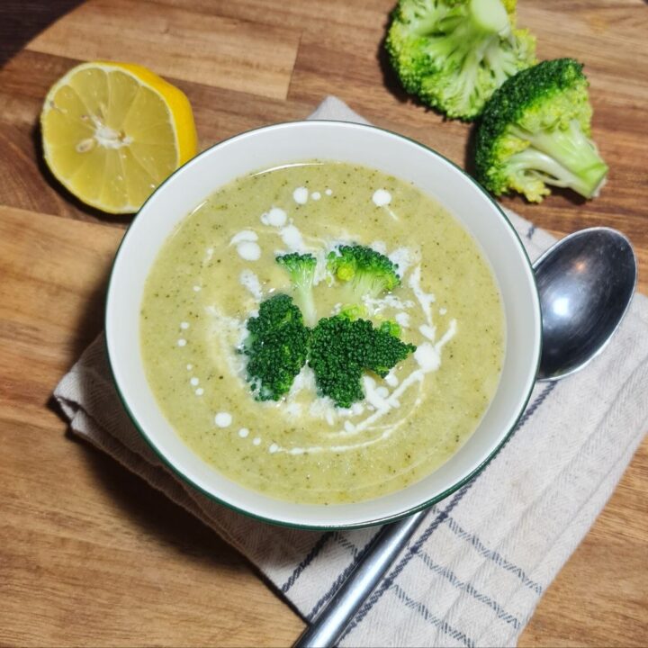 A ladle lifting creamy vegan broccoli soup with a broccoli floret from a pot.