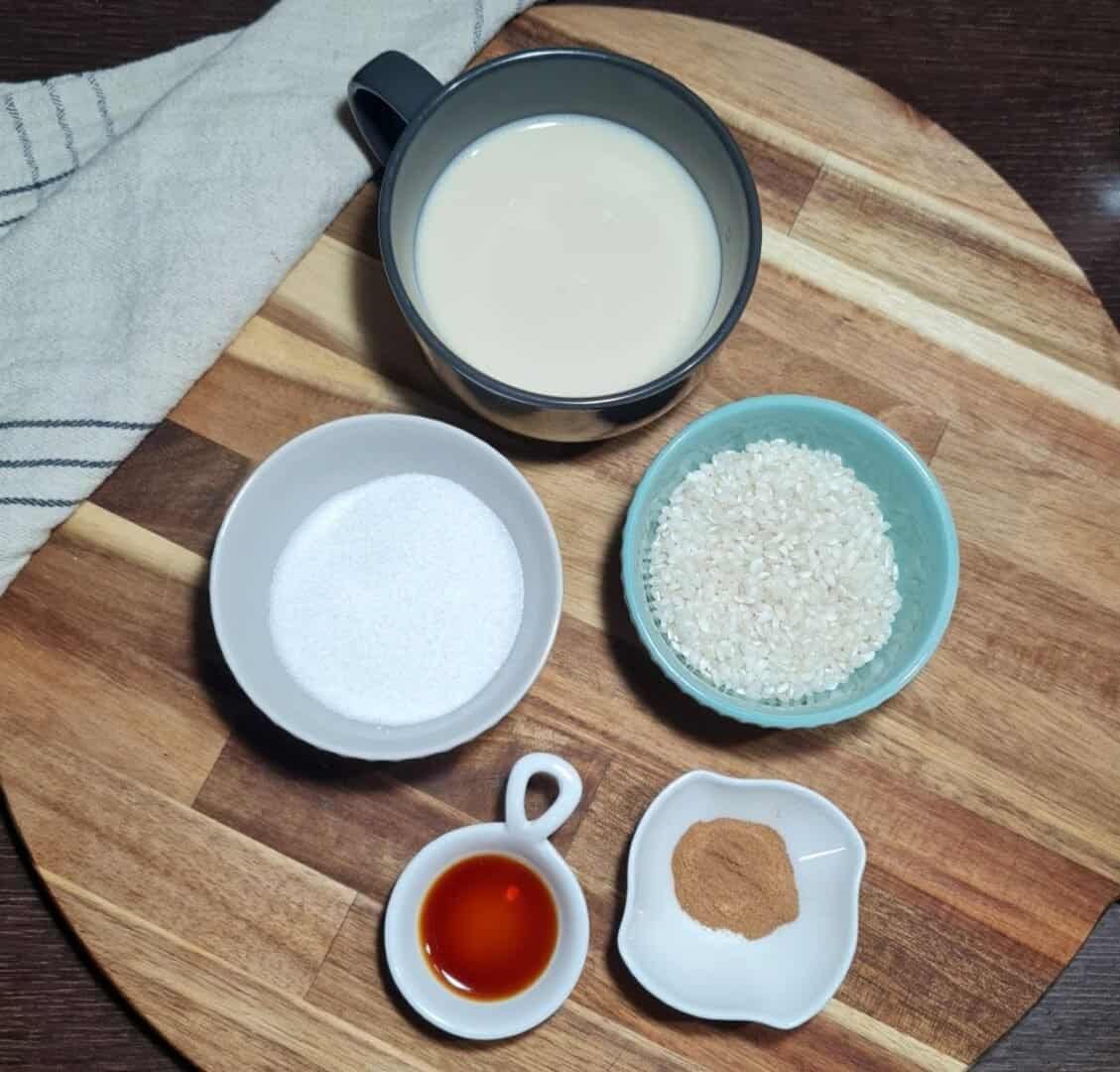  Ingredients for vegan rice pudding including plant-based milk, sugar, rice, vanilla extract, and cinnamon.