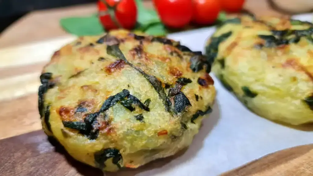 Two golden-brown vegan potato spinach patties.