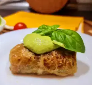 Hands carefully rolling steamed cabbage leaves stuffed with a quinoa-vegetable mixture, illustrating how to assemble Vegan Cabbage Rolls with Quinoa.