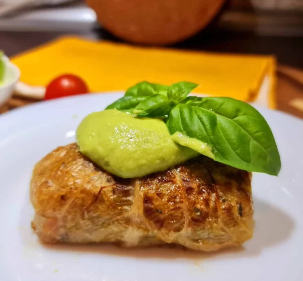 Hands carefully rolling steamed cabbage leaves stuffed with a quinoa-vegetable mixture, illustrating how to assemble Vegan Cabbage Rolls with Quinoa.