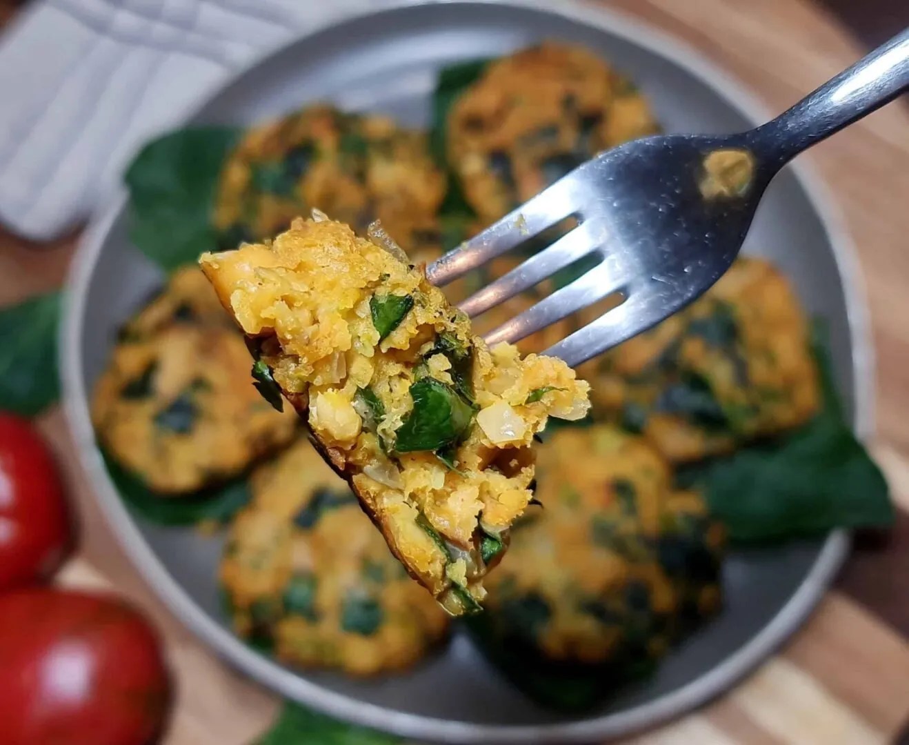 Fork holding a bite of Vegan Chickpea Spinach Patty, showing chickpeas and spinach inside.