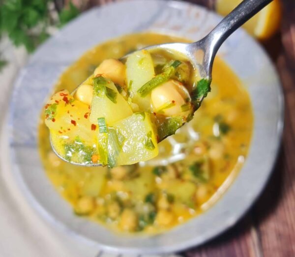 Cuchara con una porción de One-Pot Chickpea Potato Curry Soup: garbanzos, patatas y trocitos de espinaca.