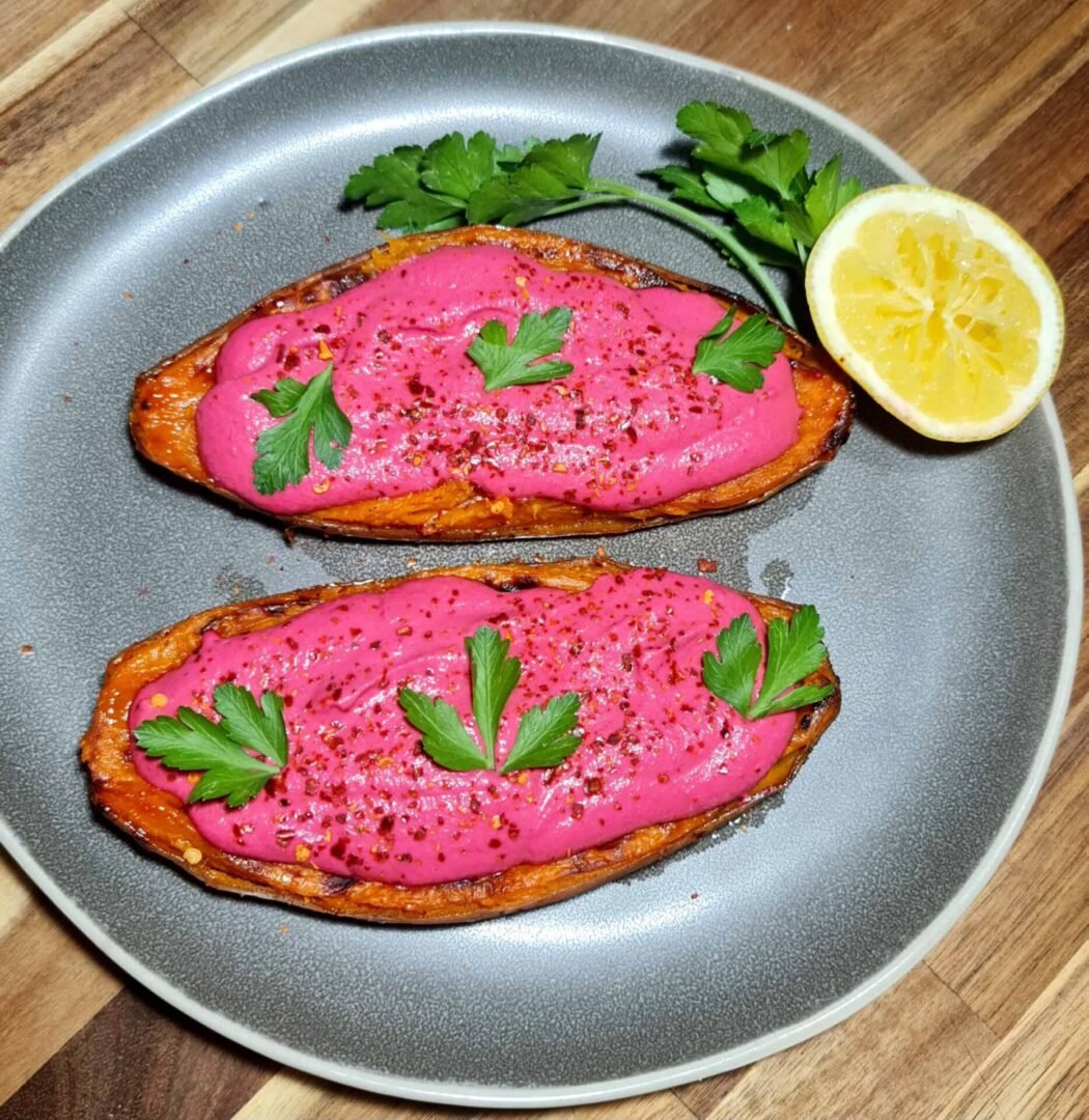Two beet sauce covered sweet potato halves on gray plate with lemon wedge and parsley garnish
