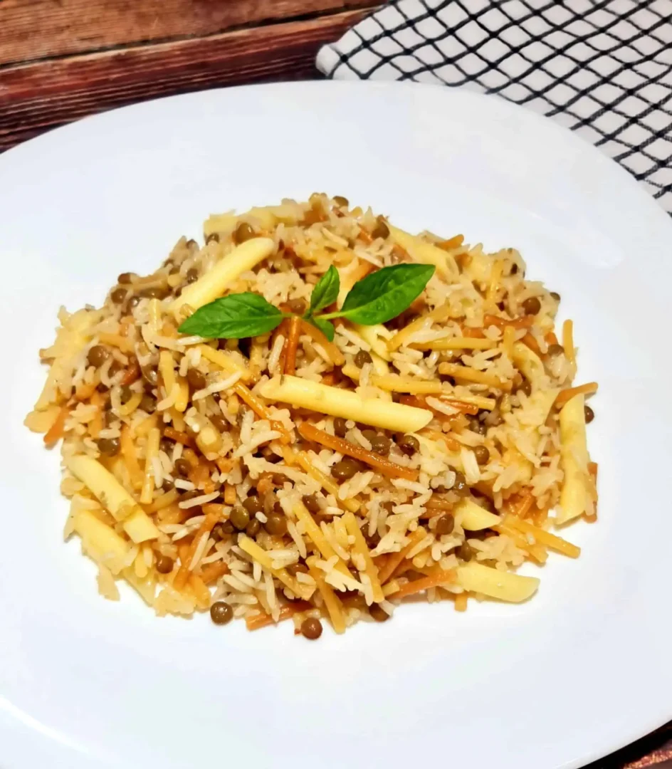 Fluffy rice vermicelli lentils and penne pilaf garnished with basil on white plate