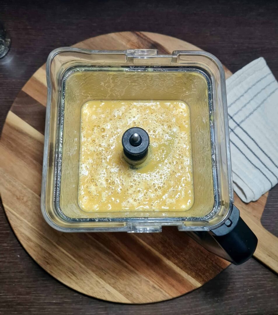 Blended bright yellow lentil soup mixture in a blender jar, showing a smooth, frothy texture after pureeing the cooked ingredients.