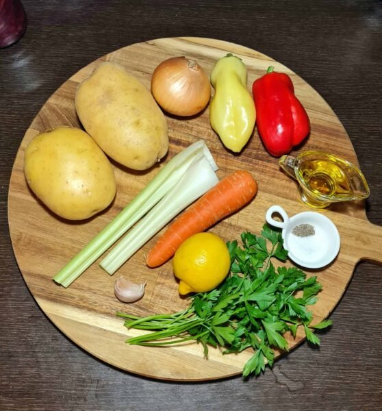 Whole ingredients, including potatoes, carrots, celery, onion, lemon, garlic, and two types of peppers, laid out for the easy vegan potato soup recipe.