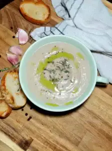 Overhead shot of creamy cauliflower and chestnut soup drizzled with olive oil and topped with thyme and black pepper.