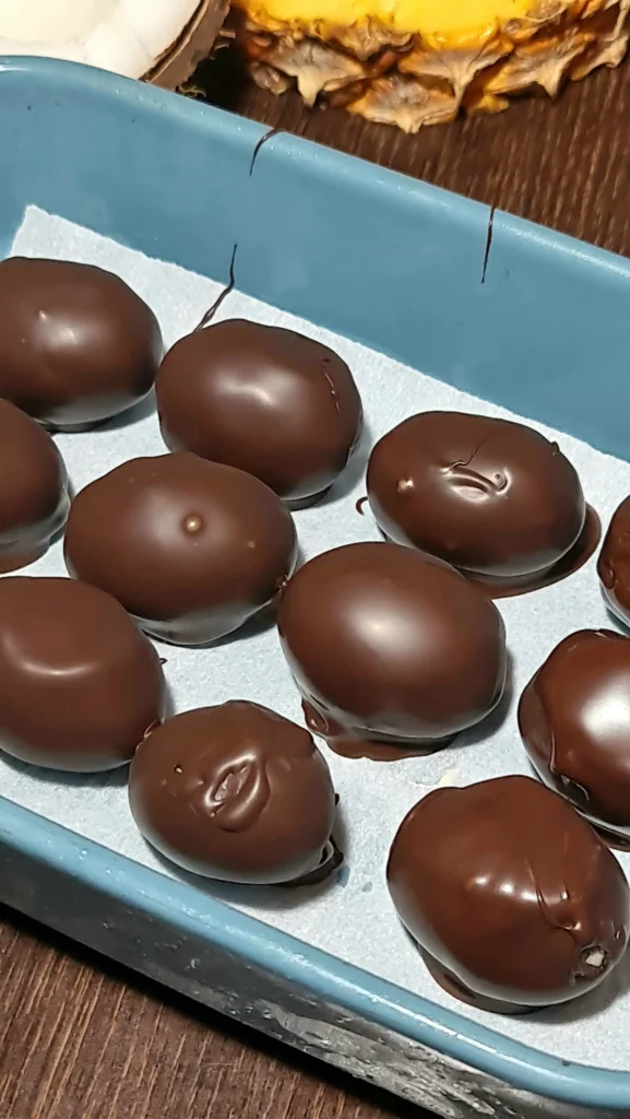 Freshly dipped chocolate-covered grapes resting on parchment paper to set, finishing the high protein chocolate yogurt grapes