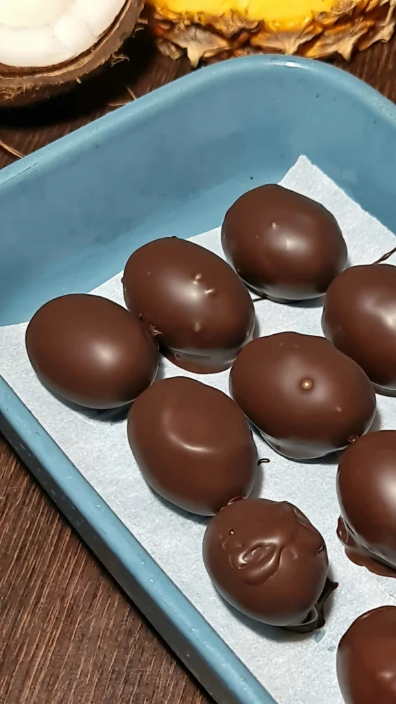 A tray of smooth, dark chocolate-covered grapes arranged on parchment paper for the high protein chocolate yogurt grapes.