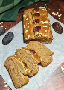 Several thick slices of vegan gluten-free sugar-free banana bread displayed on parchment paper next to whole dates.