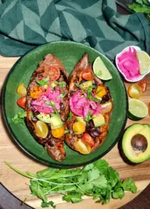 Top-down view of the colorful Blue Zones Sweet Potato Recipe served on a rustic wooden table surrounded by fresh cilantro and halved avocados.
